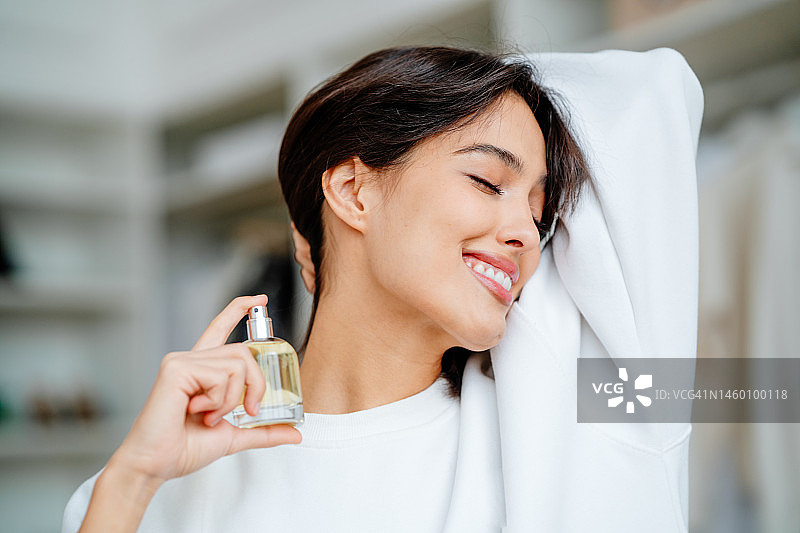 满意的，微笑的女人闭上眼睛，用手去除头发在她的脖子上涂抹香水气味图片素材
