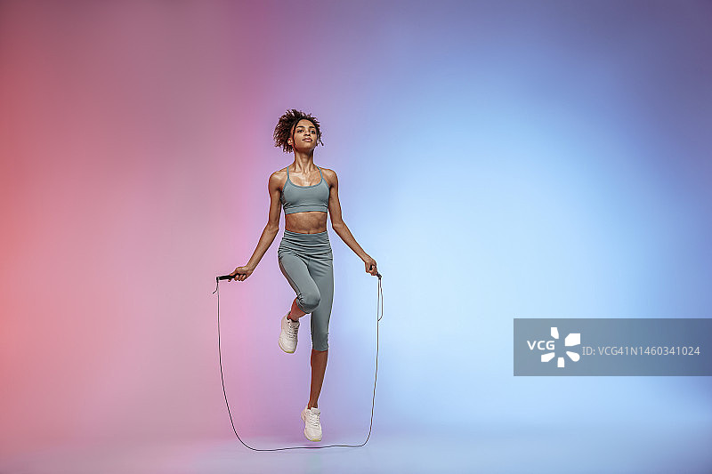 女人在跳绳工作室背景跳绳。力量和动力。最佳有氧运动图片素材