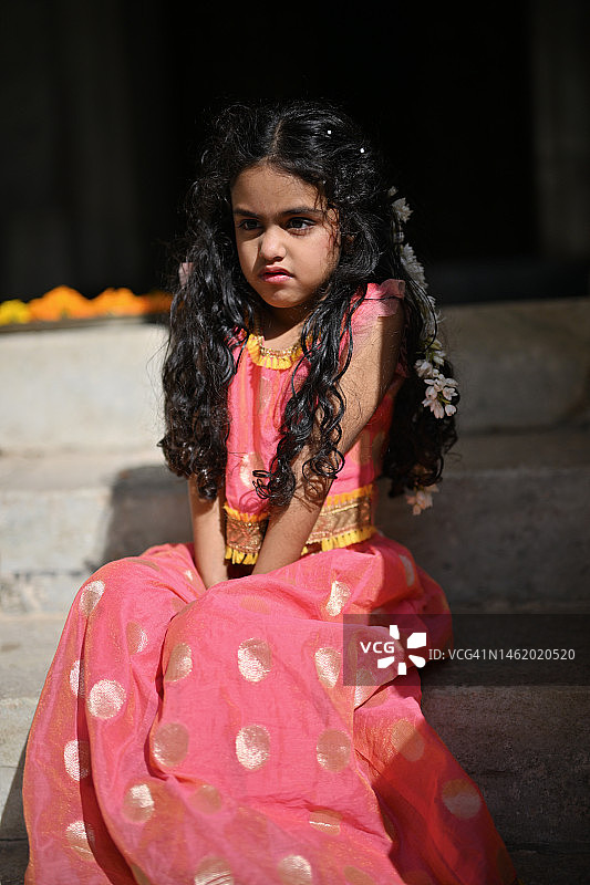 可爱的小女孩穿着传统的印度服装，愤怒的脸坐在台阶上图片素材