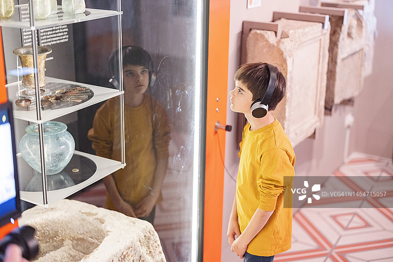 年轻的白人男孩在参观博物馆时戴着耳机听语音导游图片素材