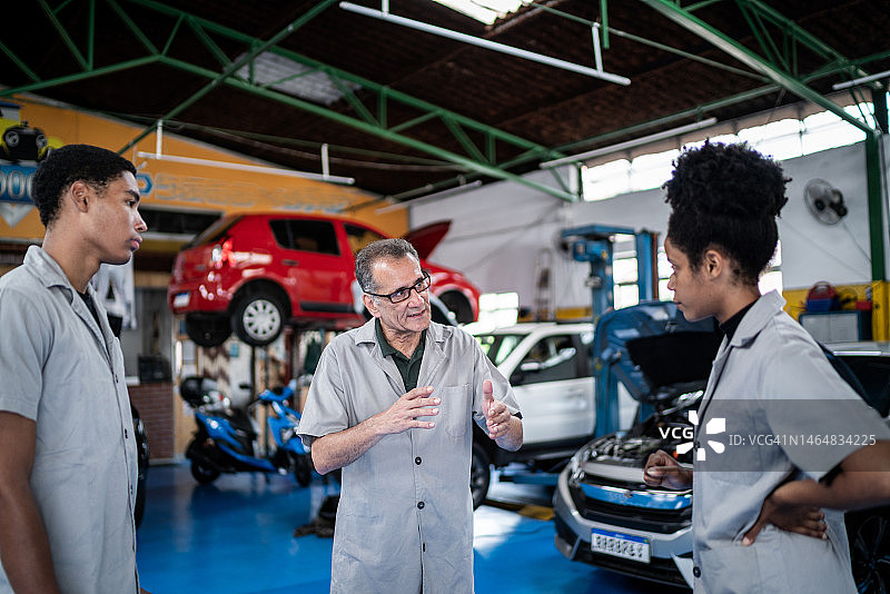 一个汽车修理工在修理厂和他的助手聊天图片素材
