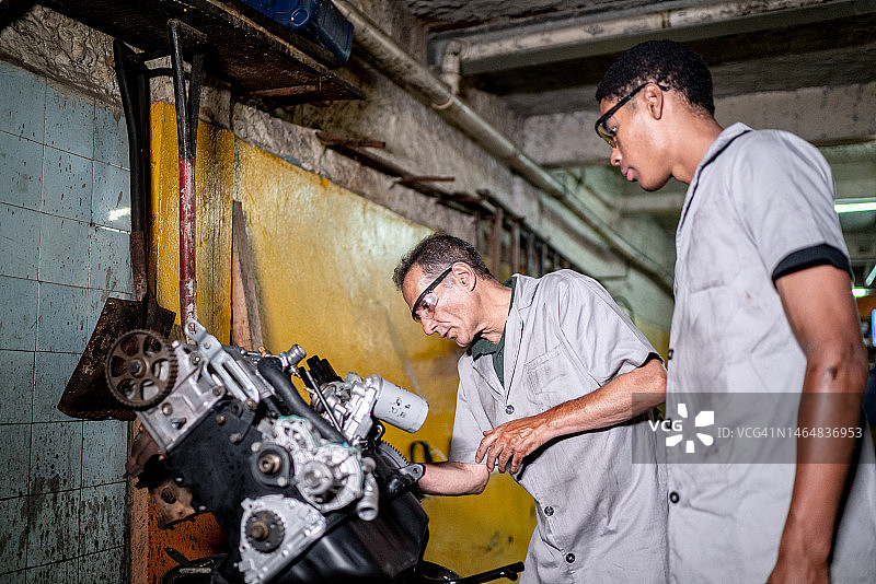 汽车机械师在修理厂分析汽车发动机图片素材