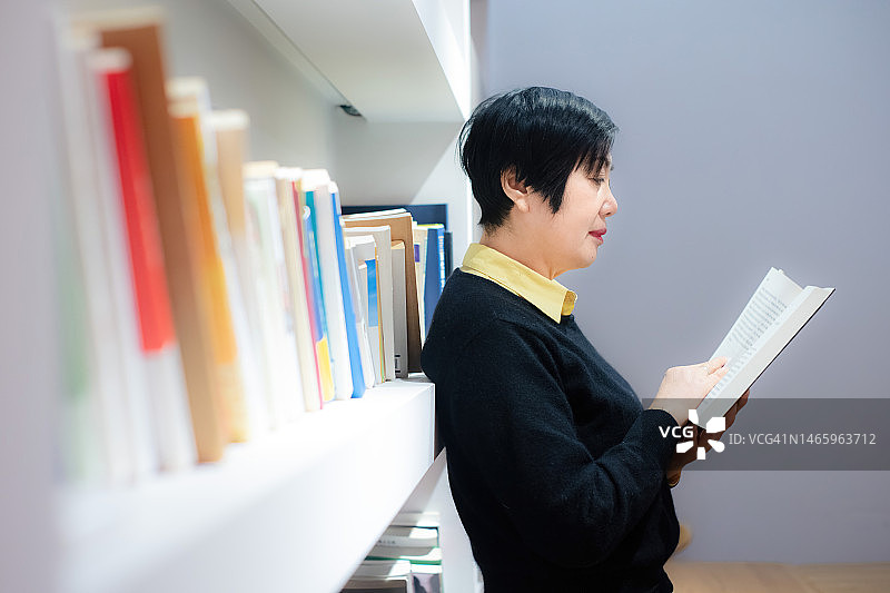 一位中国妇女站在书架前看书图片素材