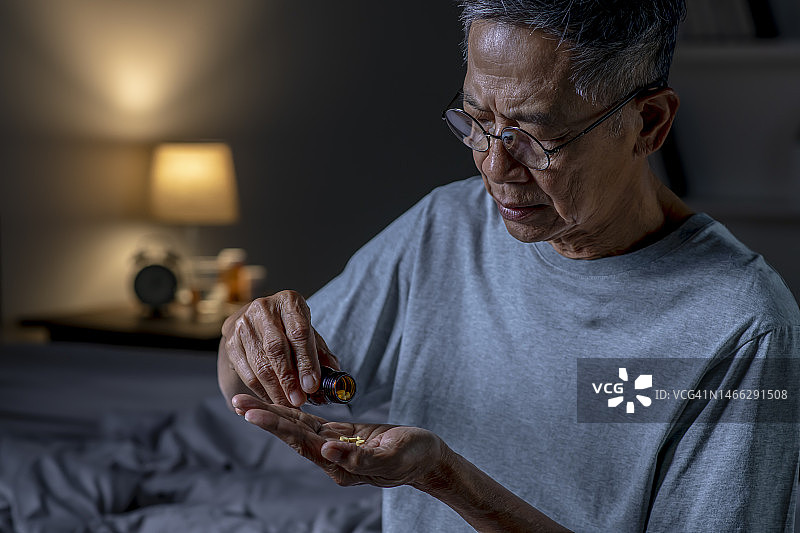 亚洲老人在卧室吃药图片素材
