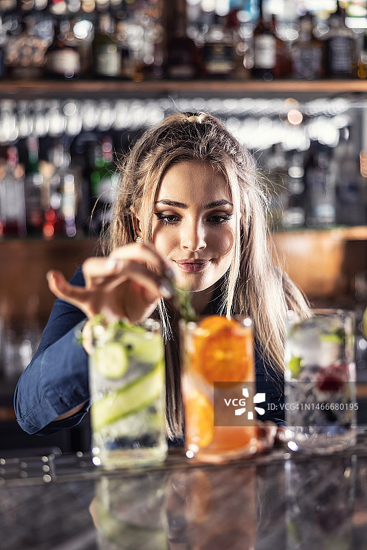 年轻的女调酒师在酒吧里制作夏日清爽的金汤力鸡尾酒。图片素材