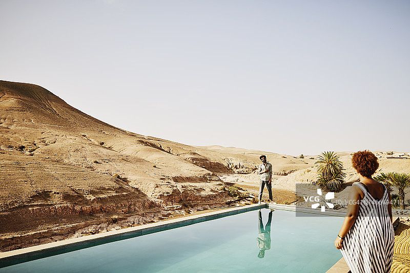 摩洛哥沙漠营地，一对微笑的情侣在泳池边放松图片素材