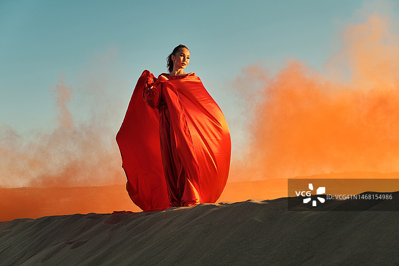 穿着红裙子的女人在沙漠里跳舞图片素材