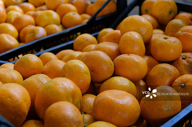 成熟的橘子放在塑料盒或容器里。素食，纯素食和生食。从仓库收获，零售和批发产品。种植有机农产品。农产品。道德消费。从农场到餐桌。蔬菜食品图片素材