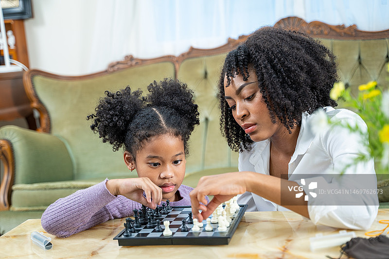 妈妈和小女儿一起下棋，玩得很开心。图片素材