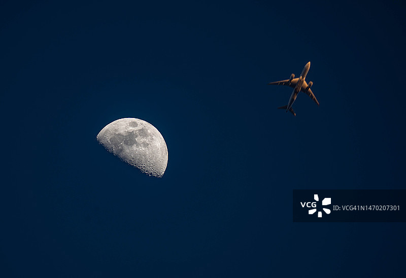 半月和飞机在日落的天空中飞行图片素材