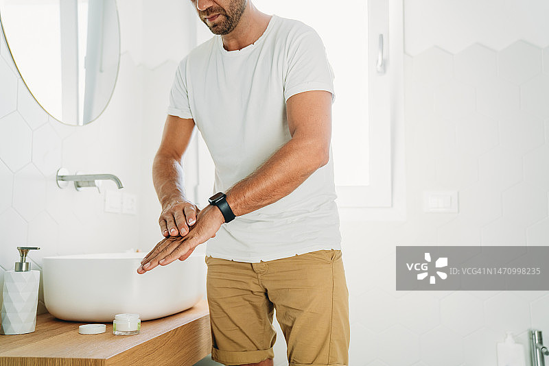 一个千禧一代的男人在浴室里用护手霜图片素材