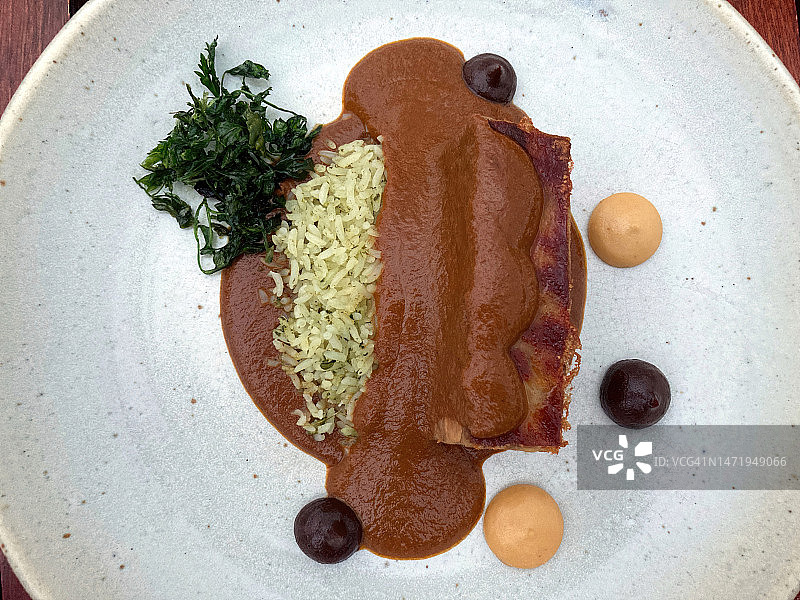 Almendrado con lechón, arroz con chepil, chiles en escabeche y almendra tostada [Almond mole sauce with confit suckling pig, rice with chepil/chipilí­n herb, pickled chilies and toasted almonds]图片素材