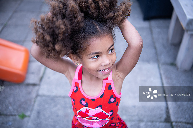 可爱和快乐的女孩在户外摆姿势，抱着她的头发图片素材