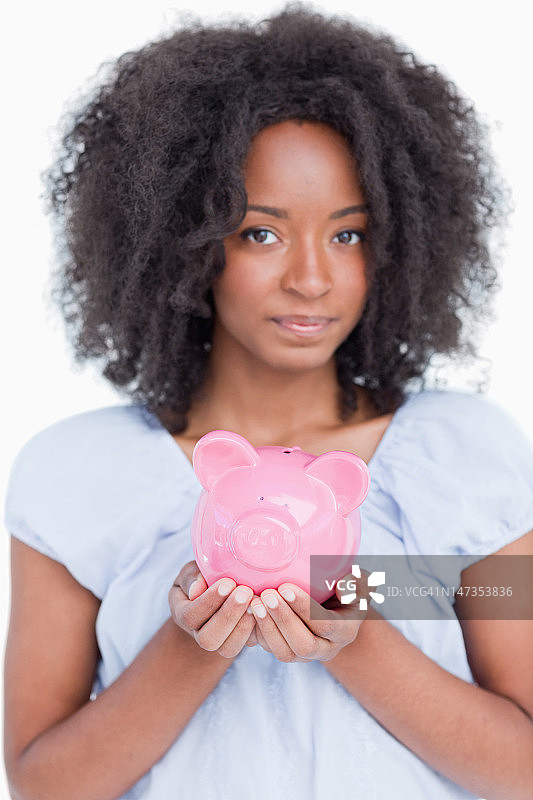 一个年轻女子紧紧抱着一个粉红色的存钱罐图片素材