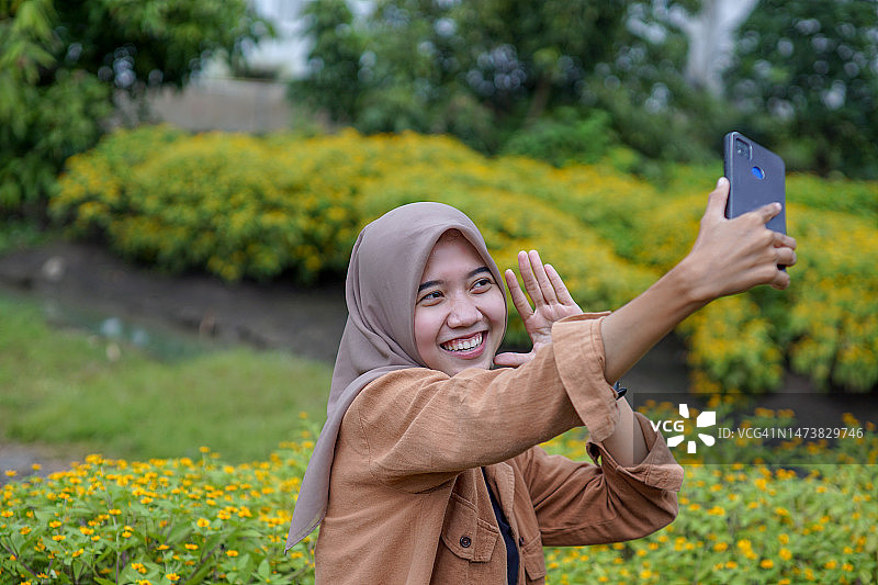 亚洲穆斯林头巾妇女做视频电话与朋友图片素材