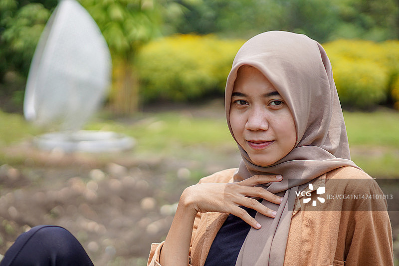 近距离拍摄的亚洲穆斯林妇女戴着头巾坐在公园的长椅上图片素材
