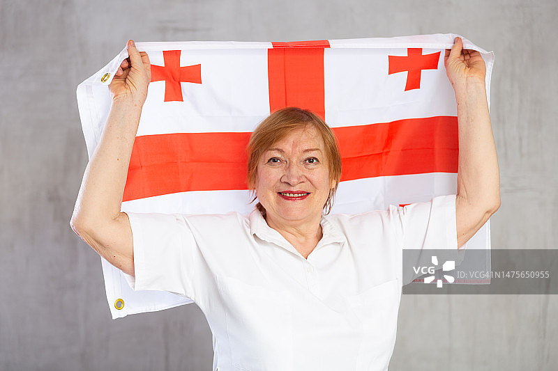 快乐的高级妇女站在格鲁吉亚国旗自信图片素材