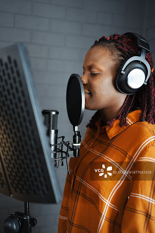 黑人女歌手戴着耳机在音乐工作室录音图片素材