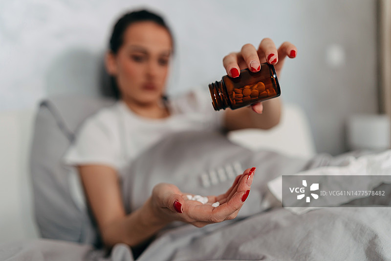生病的女人在床上吃药图片素材