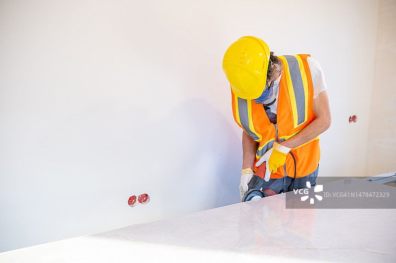 一名建筑工人在建筑工地用特殊设备加工大型花岗岩瓷砖。图片素材