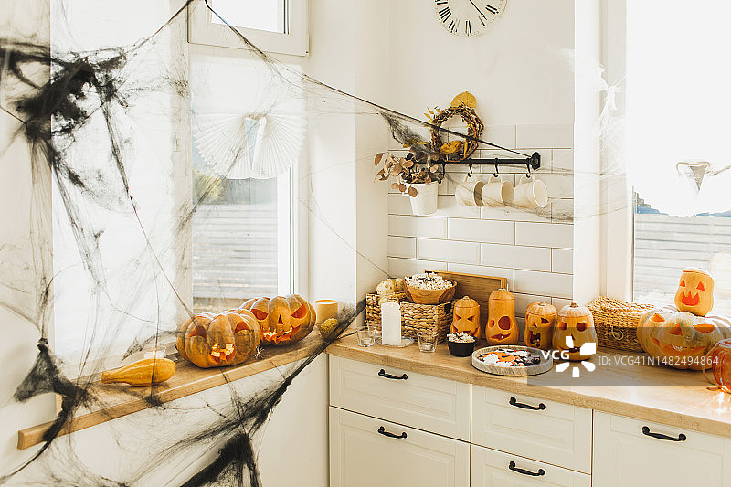 厨房里的万圣节装饰有蜘蛛网，蜡烛，可怕的南瓜灯。桌上有饼干图片素材