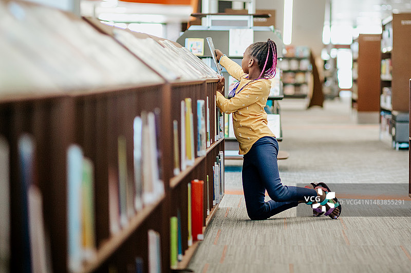 年轻的非裔美国女孩在书架上找书图片素材
