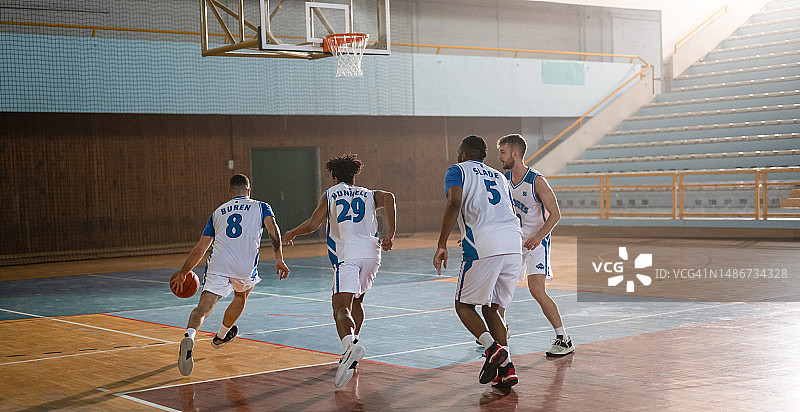 职业篮球运动员在室内球场训练图片素材