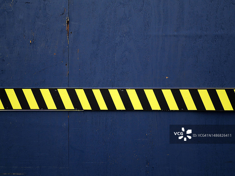 美国纽约曼哈顿，漆成深蓝色的木板，上面有黄色和黑色条纹的警告标志图片素材