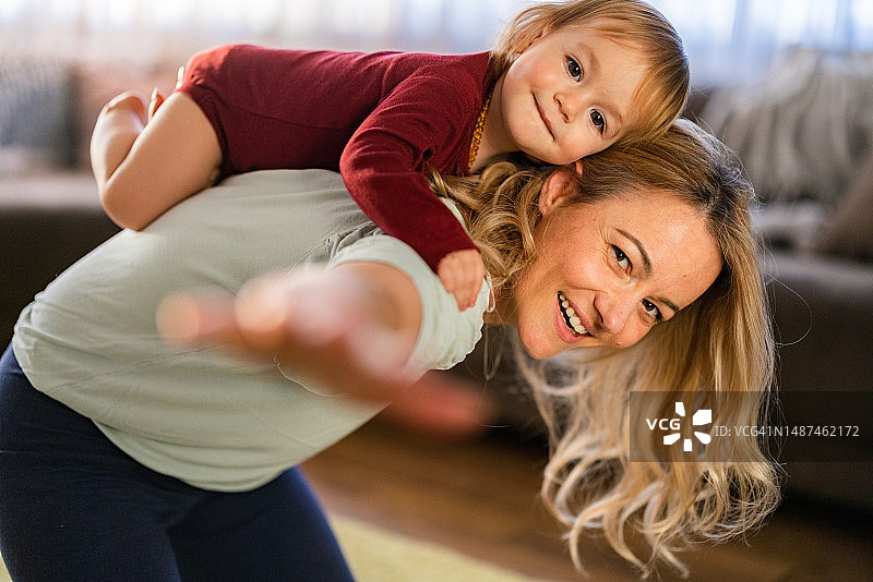 无忧无虑的母亲和她的女婴在家里玩得很开心图片素材