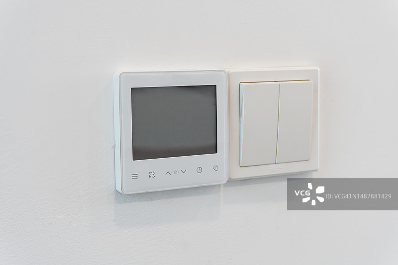 白色墙壁上的现代电灯开关和空调控制面板图片素材