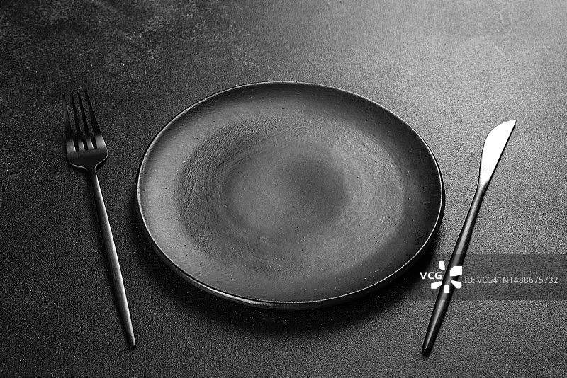 黑色餐具放在混凝土深色桌子上。餐桌，罗马尼亚图片素材