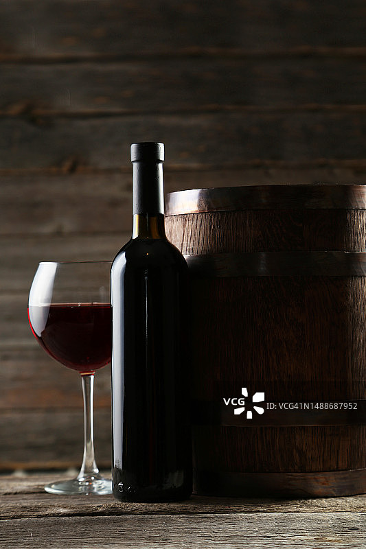 在灰色的木制背景上，有酒瓶和酒桶的红酒杯图片素材