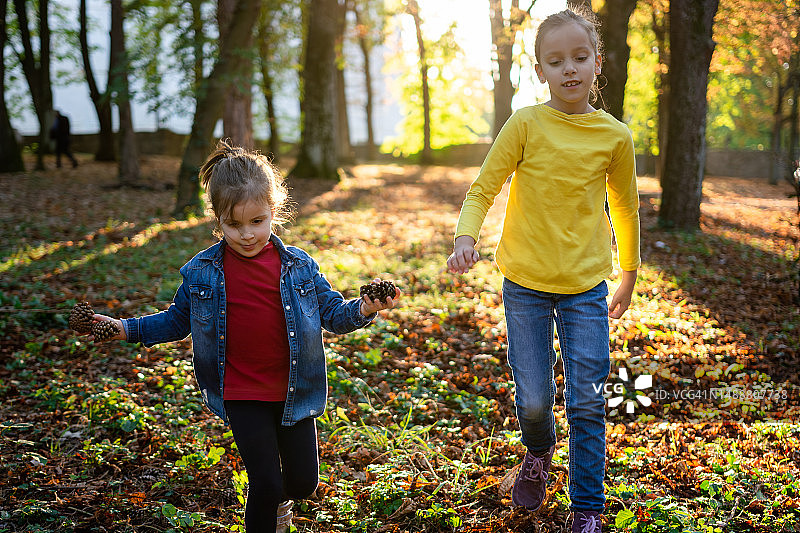 两个快乐的女孩在秋天的公园里跑步图片素材