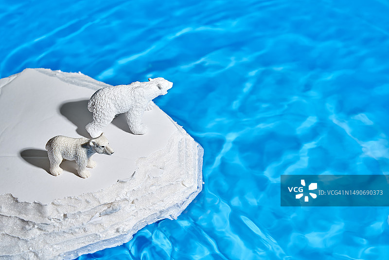 一只塑料北极熊和它的幼崽在海洋中央的一块模拟冰上图片素材