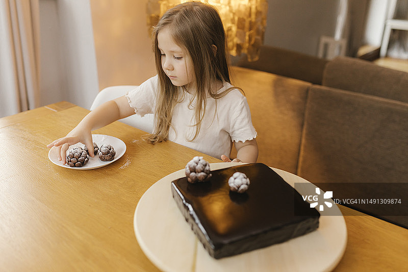 女孩在家里用松果装饰巧克力蛋糕图片素材