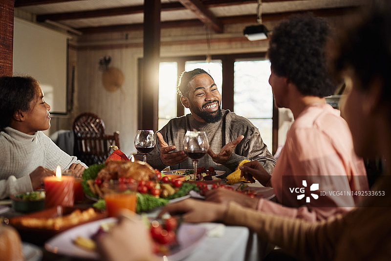 快乐的非裔美国家庭在餐桌上享用午餐。图片素材