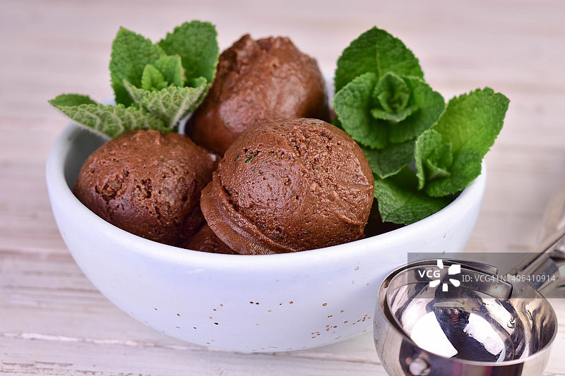 巧克力冰淇淋球和薄荷叶放在碗里。特写。图片素材