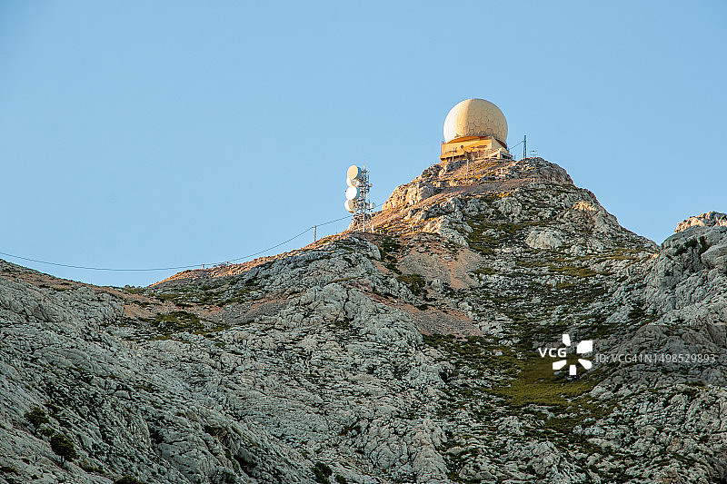 日落时山顶上的雷达圆顶站和无线电天线图片素材