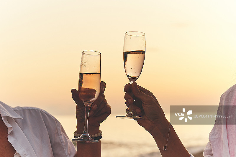 夕阳的背景下，女人手里的两杯香槟图片素材
