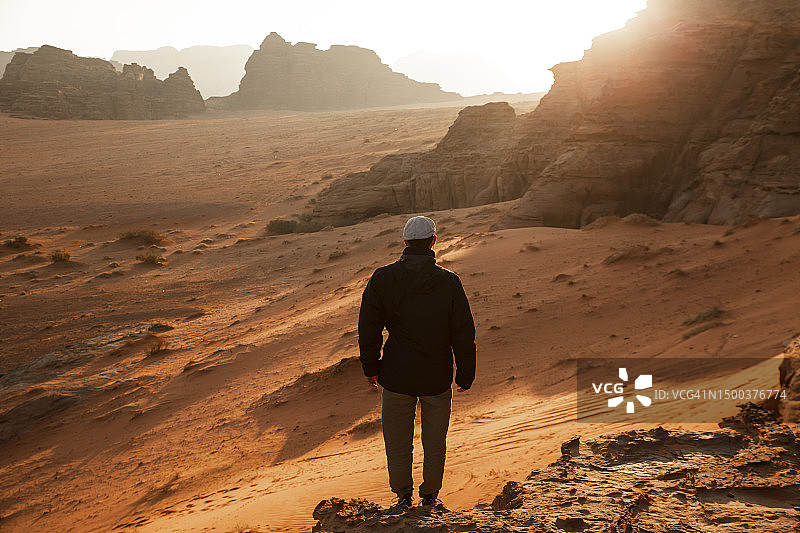 日出时站在沙漠岩石上的人图片素材