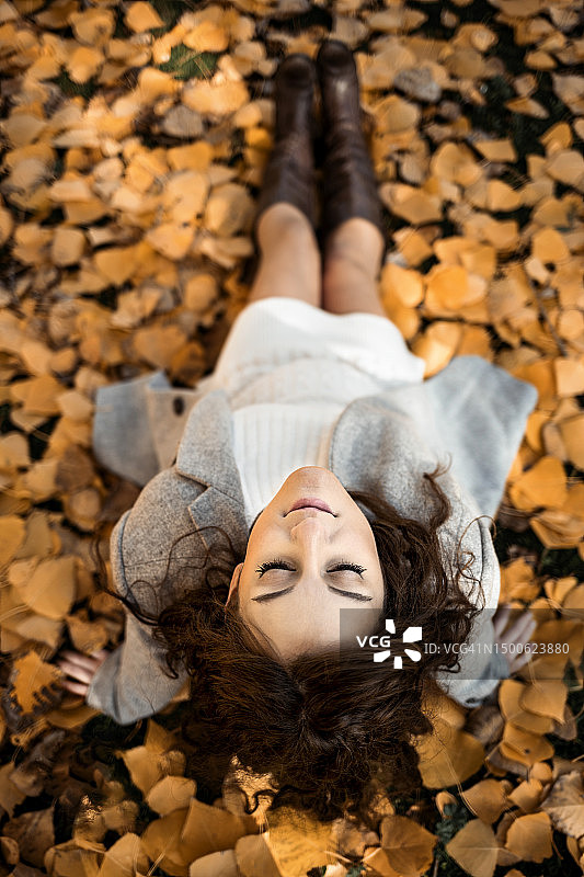 秋天的一天，一位孕妇坐在公园的地上图片素材