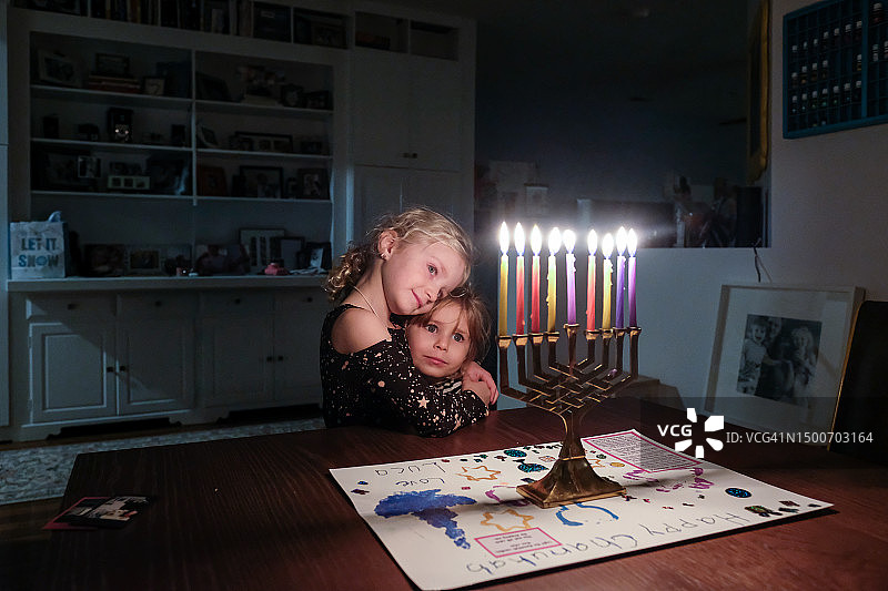 两姐妹站在一起看着光明节的烛台图片素材