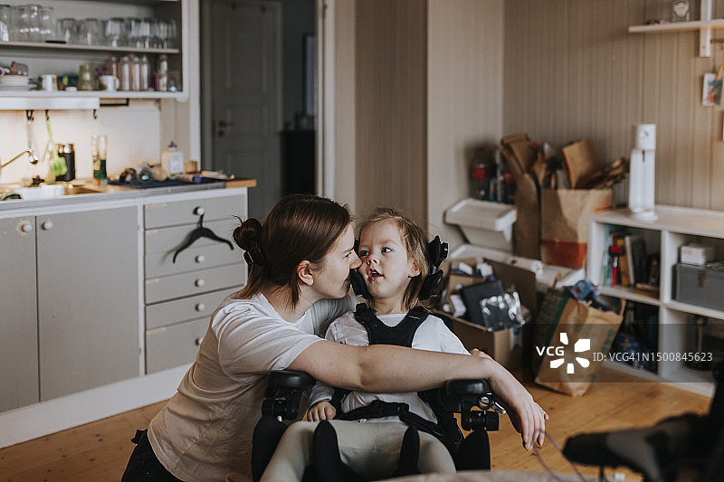 母亲在家照顾坐轮椅的残疾儿童图片素材