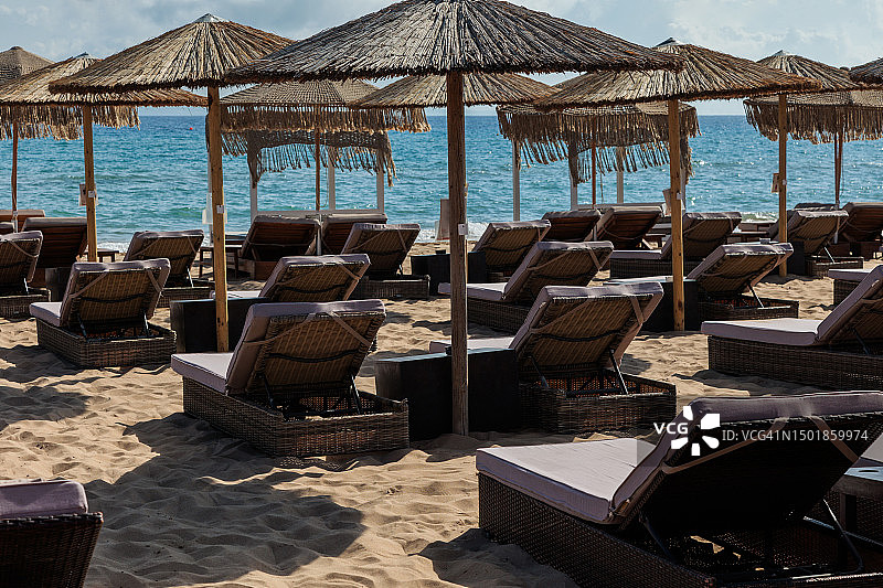 在阳光明媚的海滩上，为游客准备了一排太阳床和雨伞图片素材
