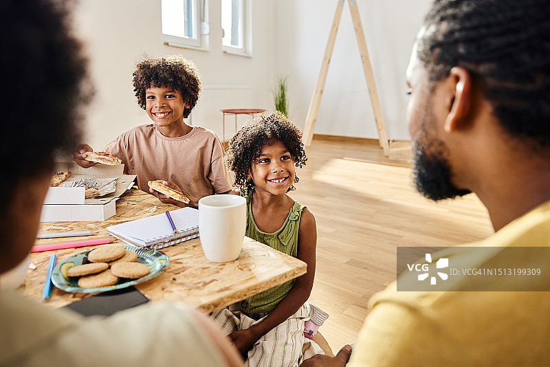 快乐的非裔美国孩子在搬家后的午休时间和父母交谈。图片素材
