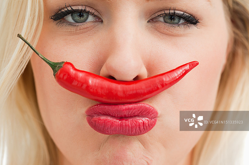 快乐的女人把辣椒放在鼻子和嘴巴之间图片素材