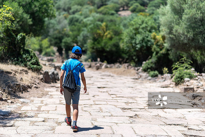 男孩背着包走在石头铺成的路上图片素材