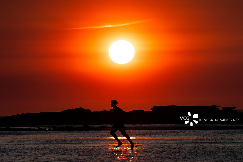 日落时分，西澳大利亚布鲁姆，一个人在凯布尔海滩上奔跑的剪影图片素材