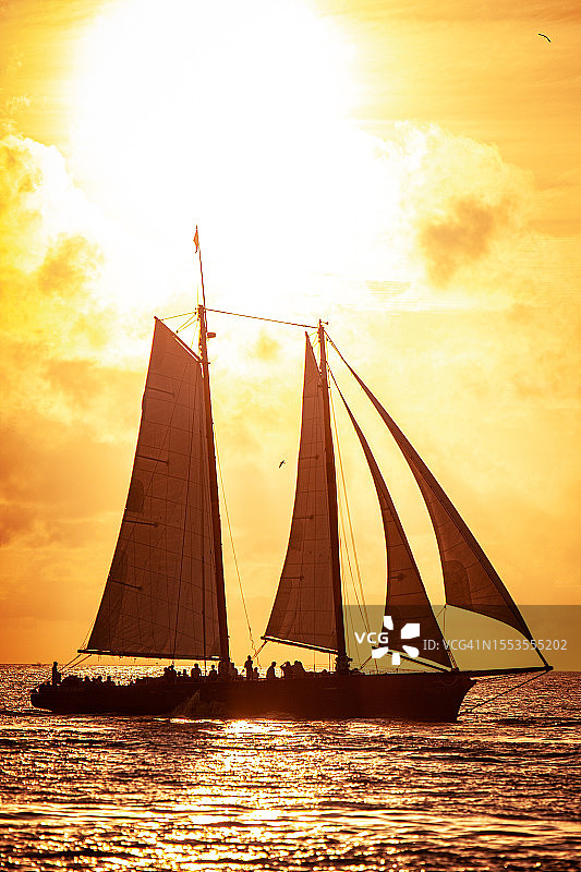 日落时帆船在海上逆天航行的剪影图片素材