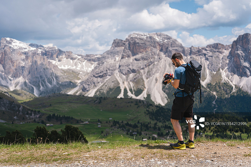 男性高加索徒步旅行者，看着他用相机拍摄的塞塞达山脉的照片图片素材